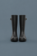 Women’s tall black rain boots on a blue-grey studio background